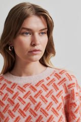 Second Female Kaja Printed Knit in coral and pale pink, close view of the woven pattern and neckline