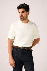Christian Kimber Apollo T-Shirt in off-white, worn by model with dark denim and western belt, front view