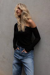 Vaenn Remsen One Shoulder Sheer Knit in black, worn by model with blue jeans against a concrete wall