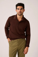 Christian Kimber Rye Long Sleeve Polo in chestnut, worn by model with olive trousers, front view