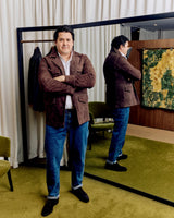Christian Kimber Rose Street Selvedge Jeans in mid indigo, worn by model in a fitting room with a brown jacket