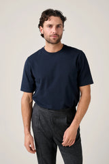 Christian Kimber Apollo T-Shirt in navy, worn by model with grey trousers, front view