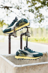 Run Of Deer Sneaker in green and yellow, pair hanging from an outdoor tap