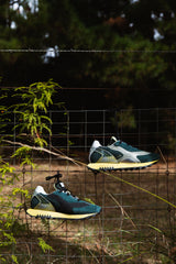Run Of Deer Sneaker in green and yellow, pair resting on a wire fence