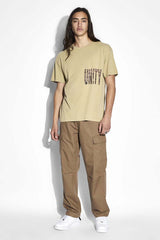 Ksubi Crowded Biggie Tee in khaki, worn by model with cargo pants, full length