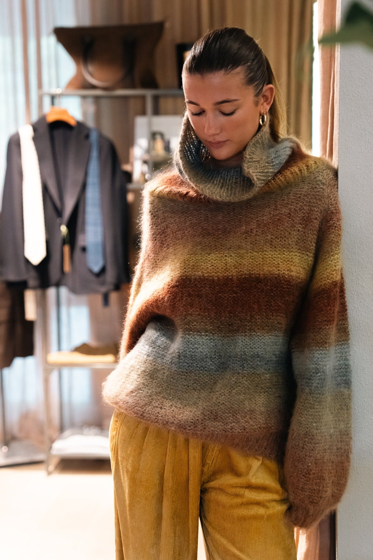 A mohair knit in ochre and rust worn with wide trousers beside the rail at Amelie & Frank's in Red Hill