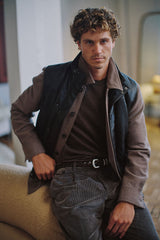 Chocolate quilted lambskin vest worn seated over a brown knit
