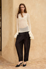 Mes Demoiselles Niko Pants in black, styled with an ivory open-knit sweater against a sandstone wall, full length
