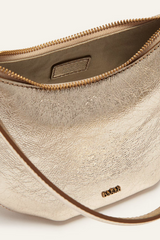 Close view of the open gold Swing bag, showing the zip and interior pocket