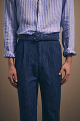 Close view of the pleated front and belted waist of the washed denim chinos