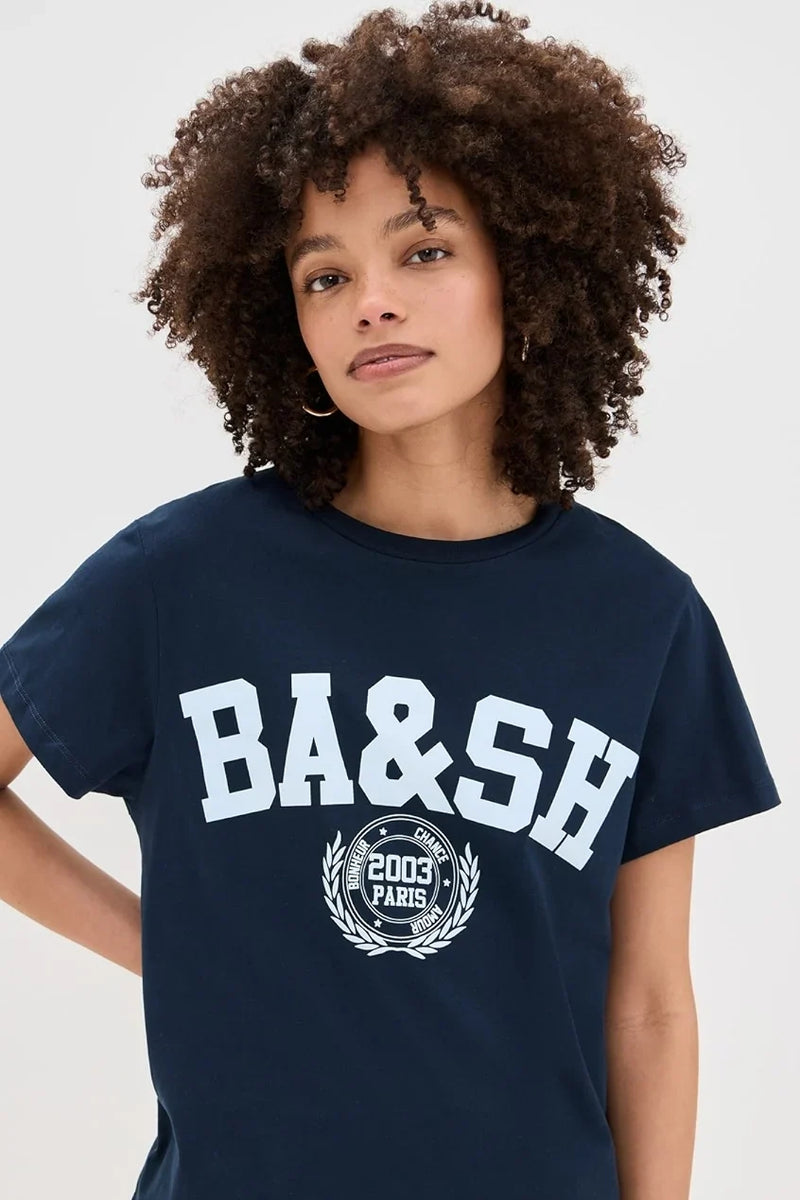 Navy tee with a pale blue BA&SH 2003 Paris varsity print, worn with grey trousers