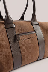 Close view of the leather handles and logo on the chocolate Weekender