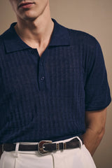 Close view of the basketweave texture, soft collar and horn buttons on the navy knit polo