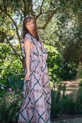 Full-length Orma dress with ruffled V neck and flutter sleeves, standing in a garden bed at Polperro