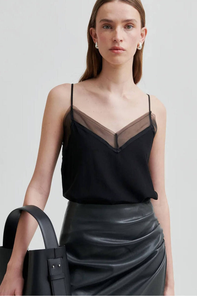 Black strappy top with a sheer V panel at the neckline, worn with a black leather skirt and bag