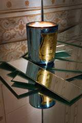 A Trudon Fir candle in celadon mirrored glass, lit on scattered mirror panes