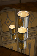 Trudon Cabinet des Miroirs candles in silver mirrored glass, the Classic, Intermezzo and Great Candle lit on a mirror against gilded panelling