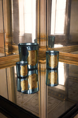 Two Trudon Fir candles in celadon mirrored glass, a tall and a small, reflected on a mirrored table