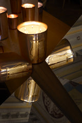 A many-wicked Trudon Galerie des Flammes candle in gold mirrored glass, lit, with the embossed gold Trudon label