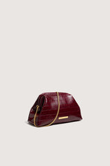 The red croc clutch at a three-quarter angle with its gold chain strap attached