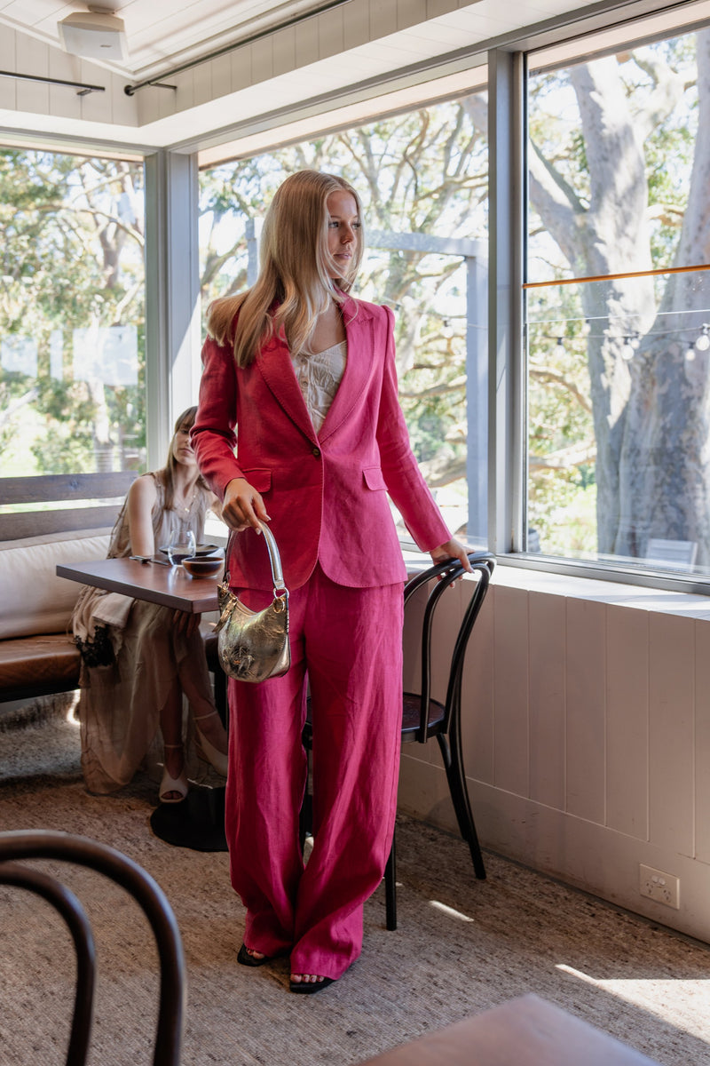 Zoe Kratzmann Crest jacket and Edit pant in rhubarb pink linen, with a gold ba&sh Swing bag, in the Polperro dining room